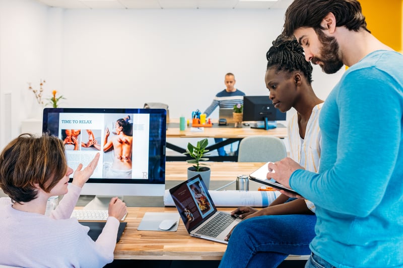 Laughing-worker-sitting-at-table-with-computer-and-discussing-project-with-colleagues-how-to-give-a-good-presentation